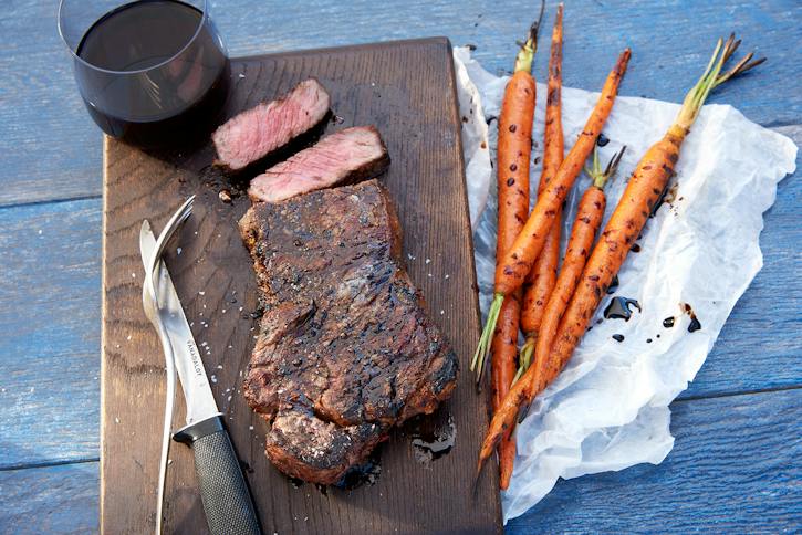 Hotový grilovaný New York Strip na prkénku s grilovanou mrkví — originální fotografie Weber